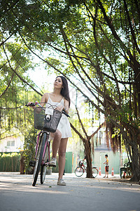 年轻美女在公园里骑自行车在自然公园户外放图片