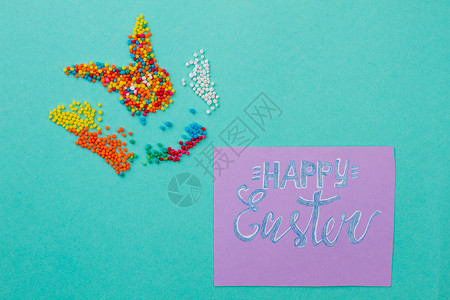 复活节快乐卡和糖果在复活节兔子的形状上撒点祝图片