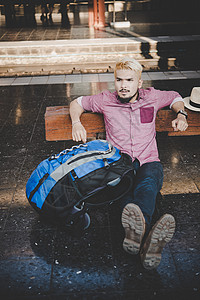 年轻的时髦人坐在火车站的木凳上男人坐在图片