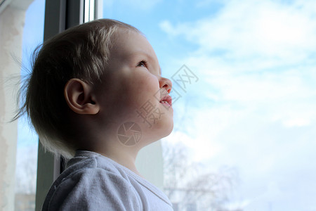一个小男孩将把窗户打开到天空背景图片