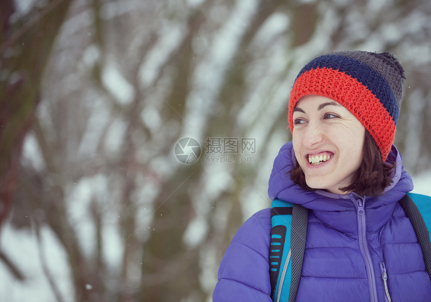 微笑的女人在公园里散步一个背着包的女孩穿过森林在白雪皑的森林背景下图片