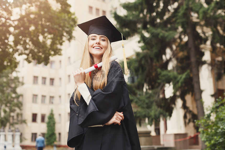 年轻微笑的女人在大学毕业那天持有文凭教育资图片