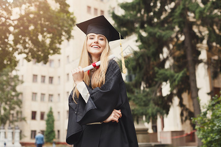 年轻微笑的女人在大学毕业那天持有文凭教育资图片