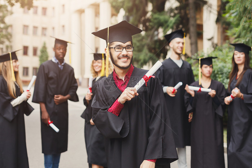年轻的微笑男在大学毕业那天与多民族的人站在一起教育资图片