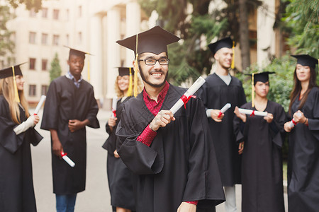 年轻的微笑男在大学毕业那天与多民族的人站在一起教育资图片