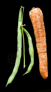 黑色背景中的青豆和胡萝卜高清图片