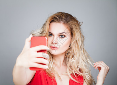 年轻美女在智能手机上拍自照片用手机制作图片