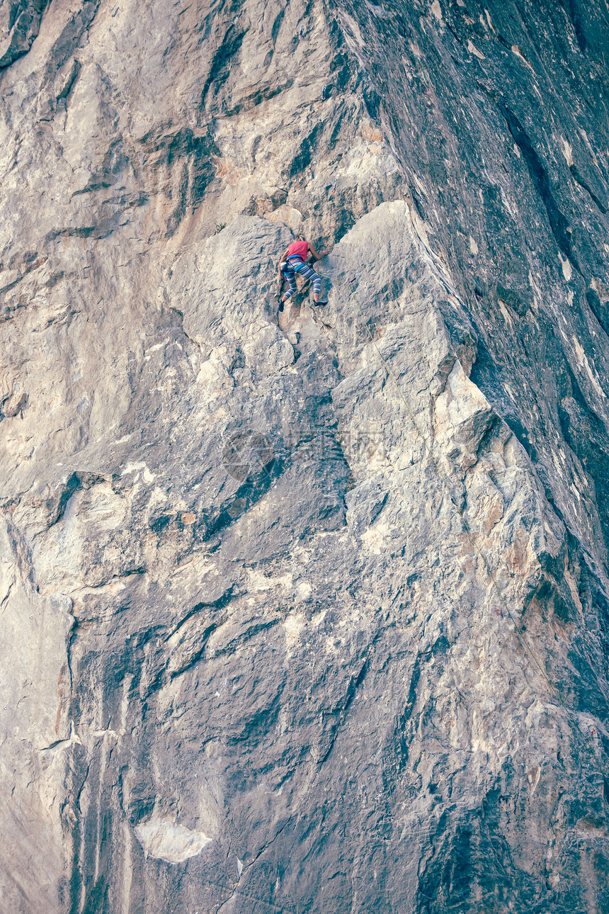 女孩爬上岩石登山者在自然浮雕上训练极限运动在大自然中进行积极的娱乐一位女士克服了艰图片