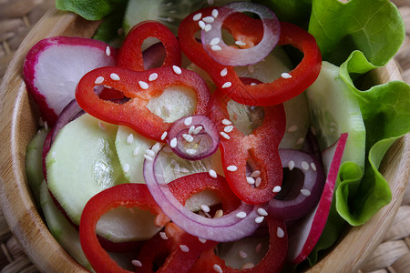 新鲜蔬菜沙拉和芝麻种子在木碗图片