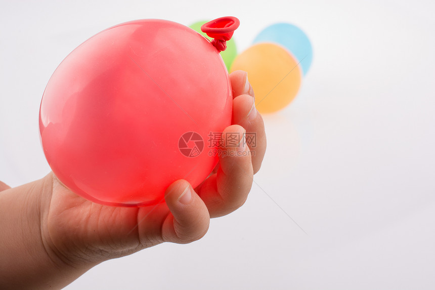 手握着一个多彩小气球白色背景图片