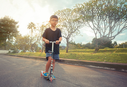 亚洲男孩在草地上玩滑板车的图片