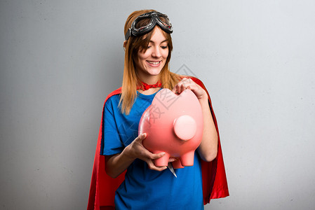 漂亮的超级英雄女孩拿着猪库在灰图片