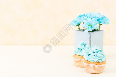 蛋糕与蓝色奶油装饰和复古破旧别致花瓶中的蓝色菊花图片