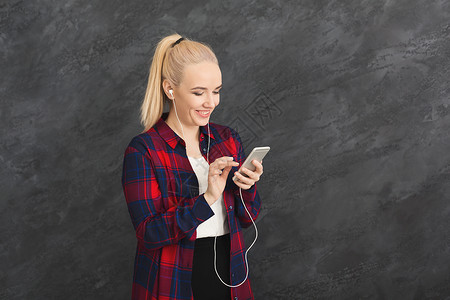 微笑的女人在智能手机的耳机中享受音乐图片