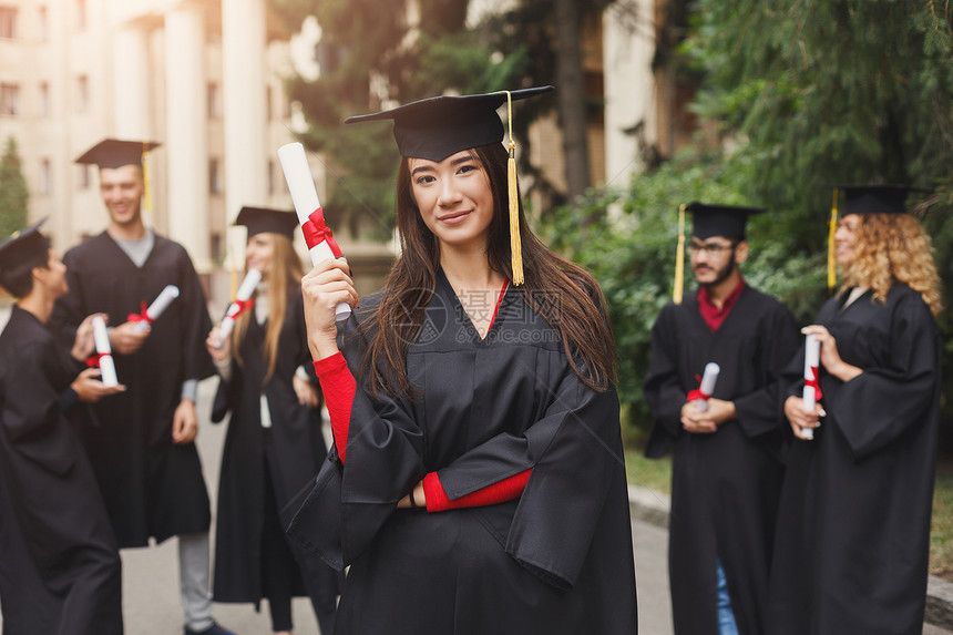 年轻严肃的女人在大学毕业那天与多民族的人站在一起教育资图片