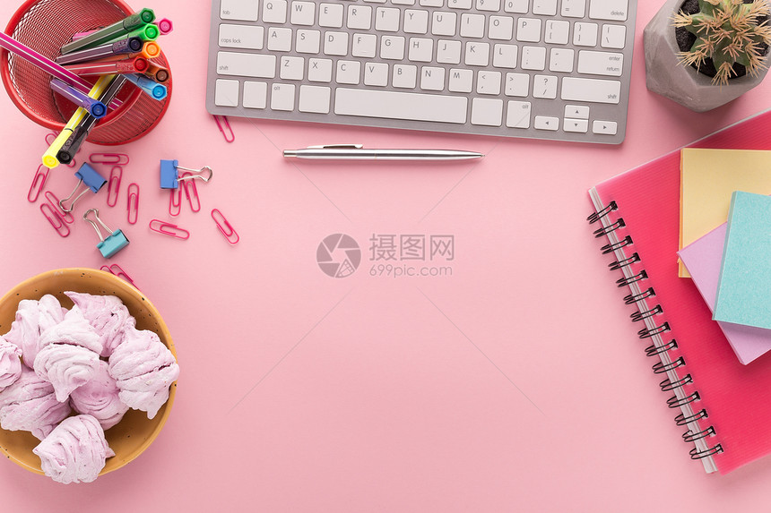 带键盘的办公桌文具记事本粉红色背景的棉花糖盘复印空间顶视图少女工作场所图片