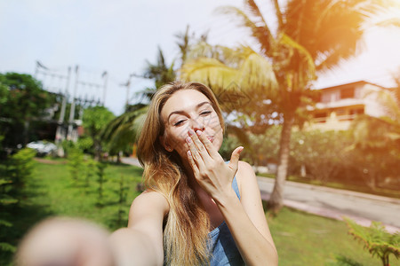 快乐的女人用空气吻拿着镜头相机自拍背景图片