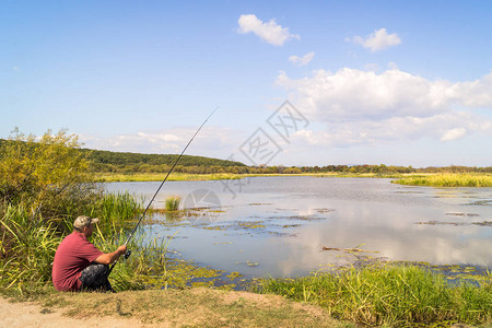 湖边的渔夫在俄罗斯远东的Khanka湖风景秀丽的风景背下钓鱼冒险图片