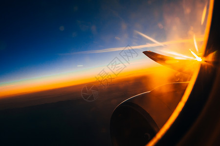 从机翼和涡轮机的飞机窗外看日出时正对图片