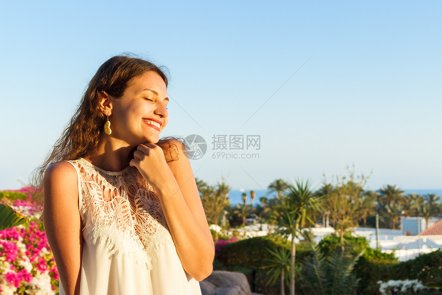 穿着白色连衣裙的漂亮女孩少年幸福的女人微笑着看太阳光明媚的夏日在图片