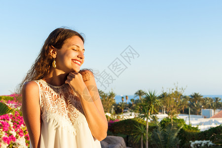 穿着白色连衣裙的漂亮女孩少年幸福的女人微笑着看太阳光明媚的夏日在图片