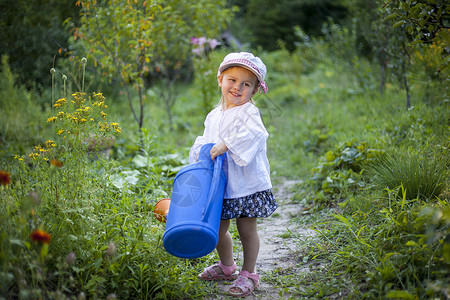 有个大水罐子的美丽的小女孩在花园图片