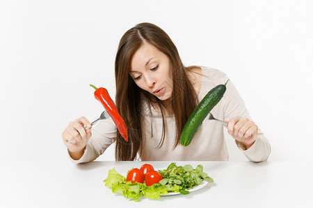 有趣的女人在餐桌上用叶子沙拉生菜放在盘子里图片