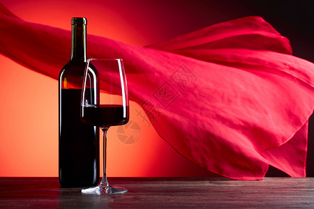 中红底素材红底玻璃和一瓶红葡萄酒红色的细布在风中飘背景