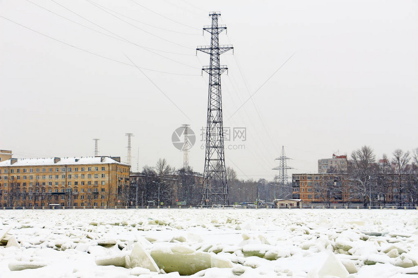 降雪期间在结冰河岸上的电力线塔图片