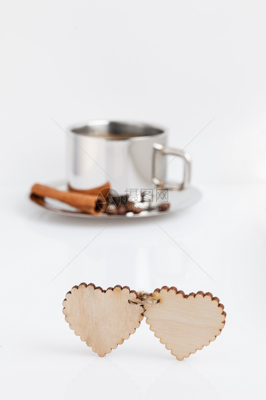 两颗木心由白色桌子上的绳索连接后面是一杯加了谷物的咖啡和一根肉桂棒情人节有文字和标图片