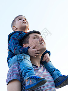 小男孩坐在他父亲的肩膀上图片