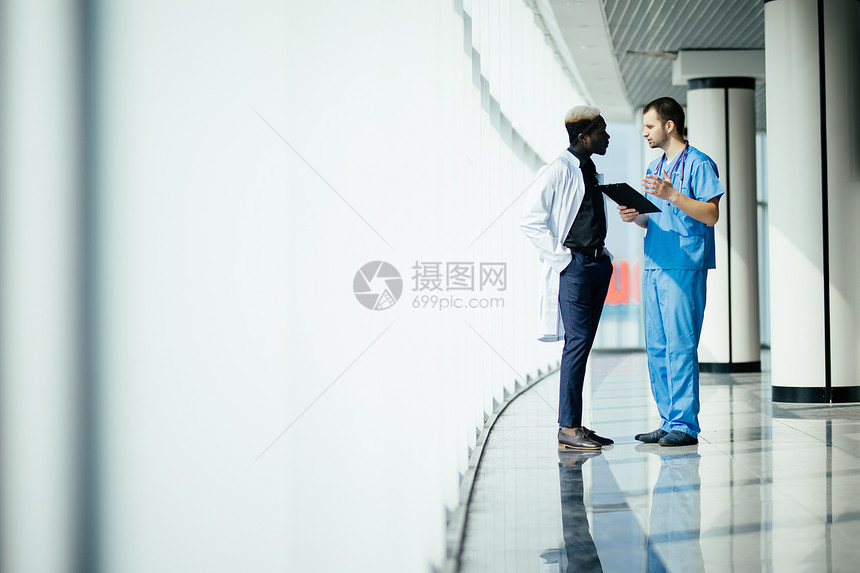 多民族医疗人员在医院走廊里讨论两名在诊图片