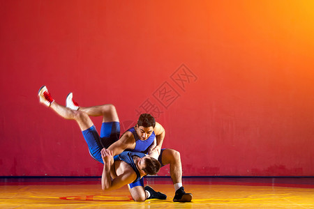两个穿着蓝摔跤裤的强壮摔跤手在健身房图片