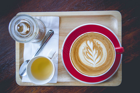 木桌上的咖啡香气拿铁艺术红杯和茶杯图片