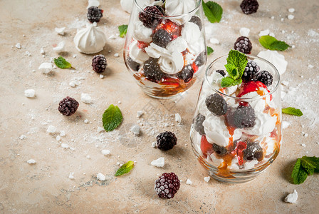 传统的英式甜点Etonmess生奶油蛋白酥皮新鲜黑莓酱汁和焦糖在浅色石桌上端酒背景图片