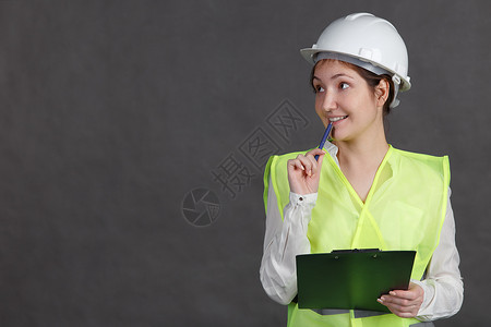 年轻女工程师身穿防护头盔和腰衣微笑地用图片