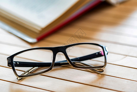 关闭木桌表面的眼镜和开放书读取图片