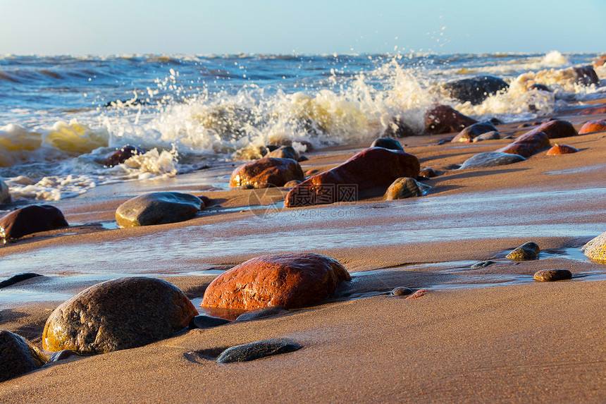 多风的海岸上的沙子和石头图片