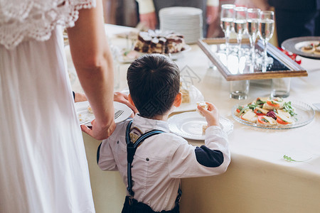 小男孩在婚宴桌上吃食物开胃菜庆祝活动中的豪华餐饮在活动概念中提图片