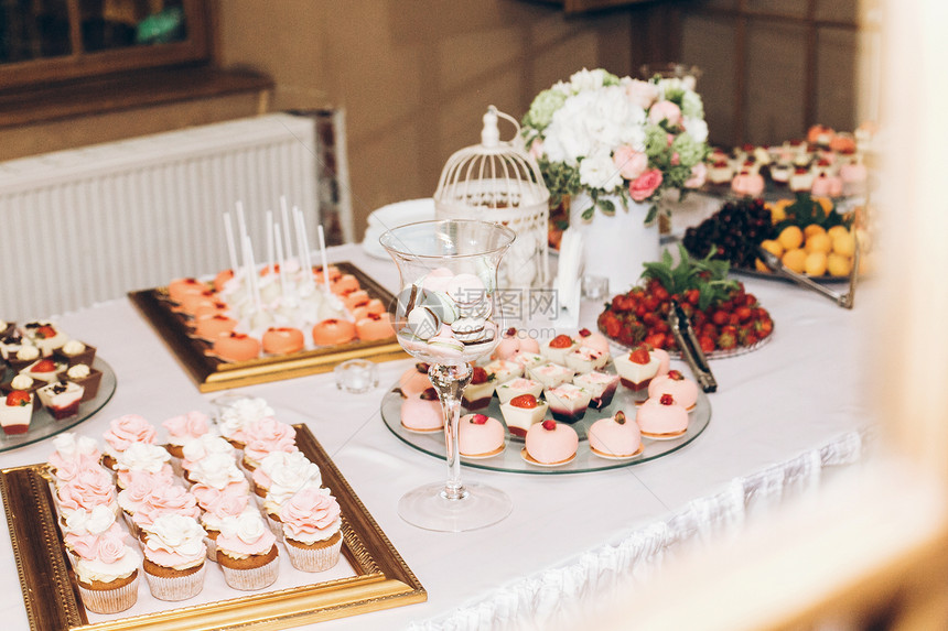 美味的马卡龙在玻璃和纸杯蛋糕流行音乐和婚宴桌上的糖果糖果条用于庆祝活动和淋浴的美味粉红色糖果图片