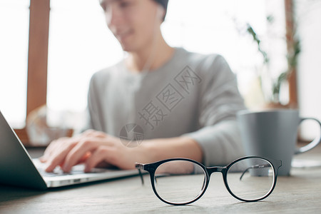 一个人坐在桌旁工作的视图他正在使用笔记本电脑工作除了笔记本电脑图片