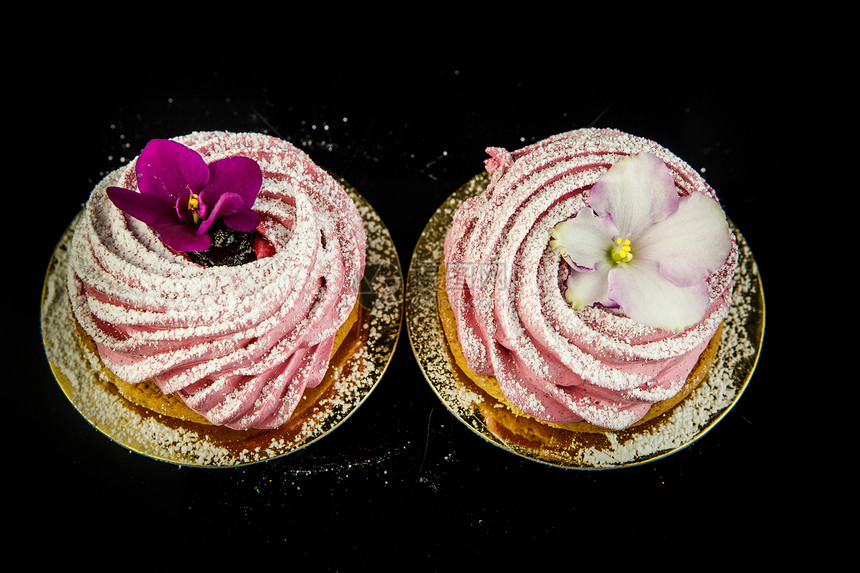 以紫罗兰和白色花朵装饰的粉红斑点饼干上面黑色镜图片