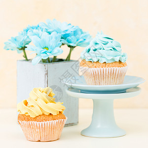 蓝色和黄色奶油装饰和破旧别致花瓶中的蓝色菊花的蛋糕图片