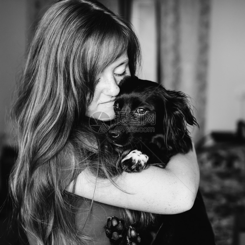 带着一只黑狗在她的怀里拥抱着黑色和白色的摄影师图片