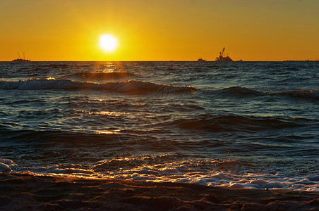 在波罗的海浪的冲浪中海岸上日出辉煌图片
