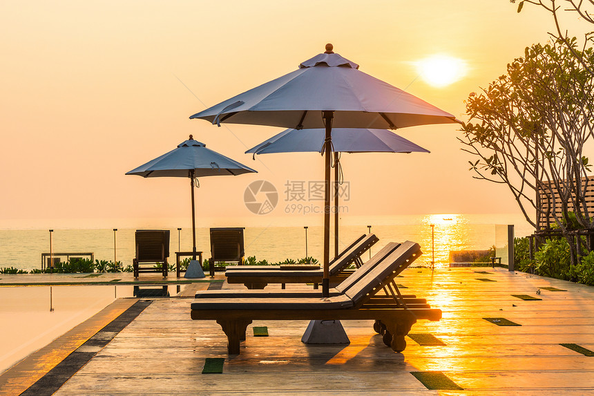 美丽的雨伞和椅子在日出时在酒店和度假胜图片
