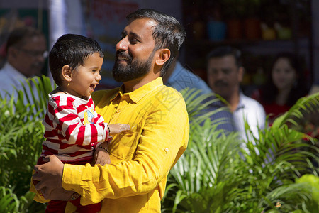 年轻的印度男人和儿子笑着微笑在浦图片