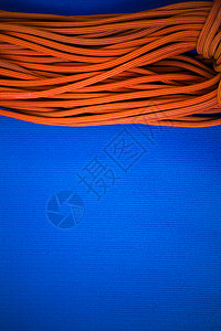 在蓝色背景上攀爬和攀爬的橙色绳索用于积极运动的绳图片
