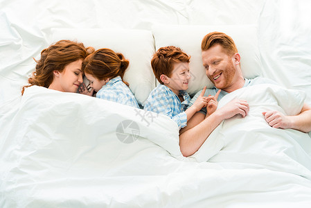 有两个孩子躺在床上的幸福家庭图片