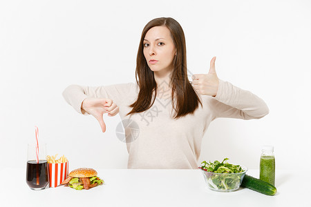 女人用绿色排毒冰沙玻璃碗里的沙拉瓶子里的黄瓜汉堡可乐在白色背景下隔开图片